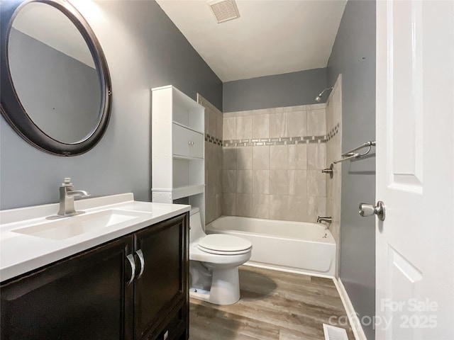 bathroom featuring visible vents, toilet, tub / shower combination, vanity, and wood finished floors