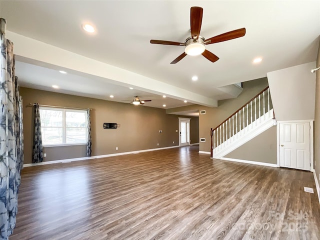 unfurnished living room featuring wood finished floors, a healthy amount of sunlight, baseboards, and stairs