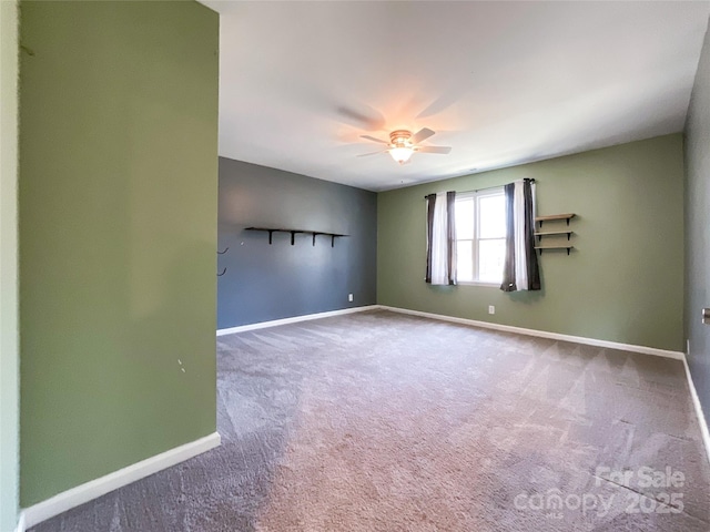 carpeted spare room featuring baseboards and a ceiling fan