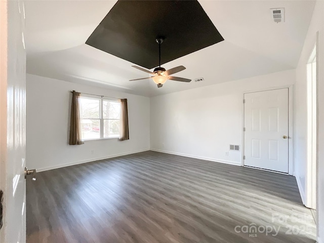 spare room with ceiling fan, dark wood finished floors, visible vents, and baseboards