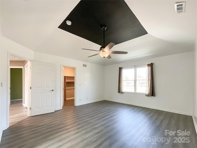 interior space featuring dark wood-style floors, visible vents, ceiling fan, and baseboards