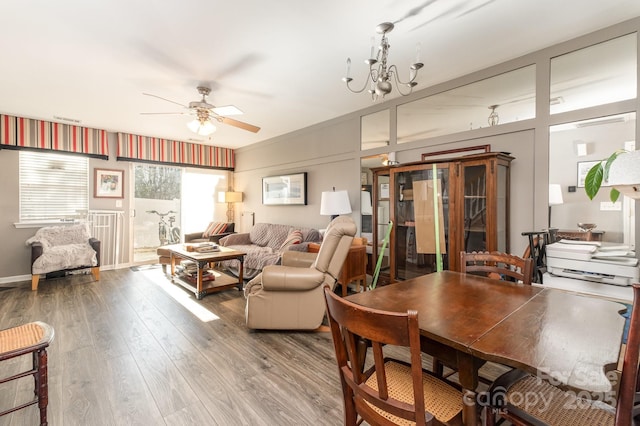 living area with ceiling fan with notable chandelier and wood finished floors