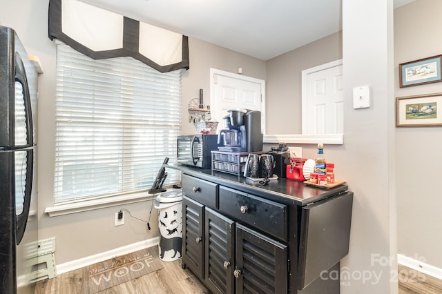 kitchen with black appliances, light wood-style flooring, baseboards, and dark cabinetry