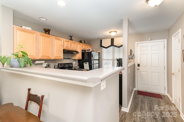 kitchen with range with electric stovetop, light brown cabinetry, dark wood-type flooring, freestanding refrigerator, and a peninsula