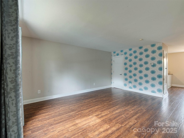 empty room with dark wood finished floors, baseboards, and wallpapered walls