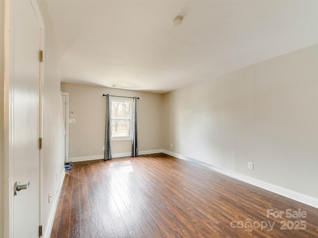 empty room featuring baseboards and dark wood finished floors