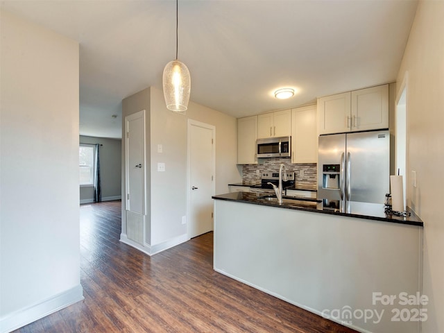 kitchen featuring white cabinets, decorative backsplash, dark countertops, dark wood-style floors, and stainless steel appliances