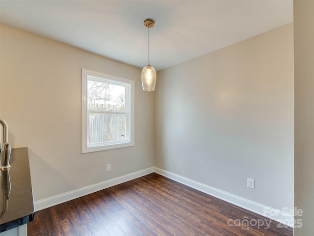 unfurnished dining area with dark wood finished floors and baseboards