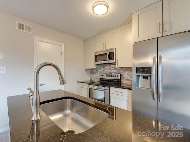 kitchen with tasteful backsplash, visible vents, white cabinets, appliances with stainless steel finishes, and a sink