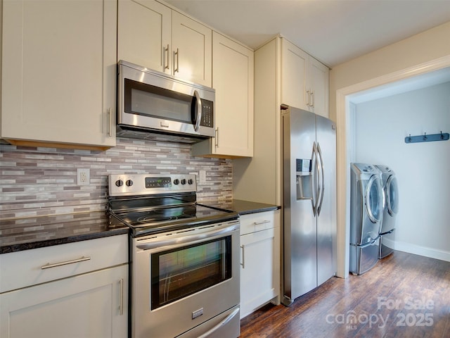 kitchen featuring baseboards, decorative backsplash, dark wood-type flooring, washing machine and clothes dryer, and stainless steel appliances