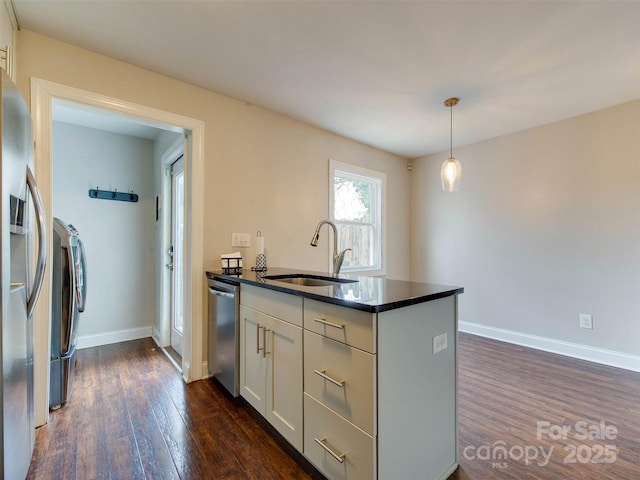 kitchen featuring pendant lighting, dark countertops, appliances with stainless steel finishes, dark wood-type flooring, and a sink