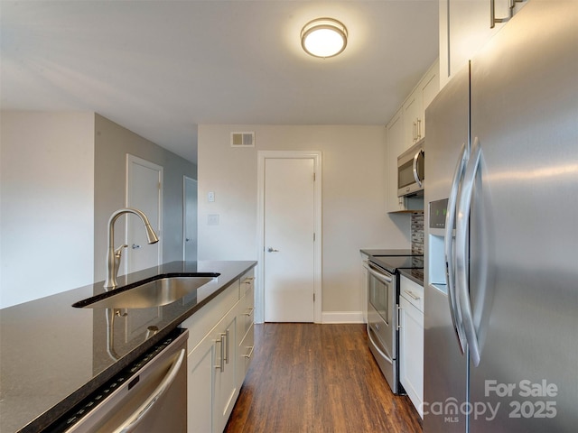 kitchen with visible vents, dark wood finished floors, dark stone counters, appliances with stainless steel finishes, and a sink