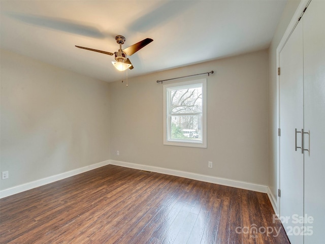 unfurnished bedroom with a closet, dark wood-style flooring, ceiling fan, and baseboards