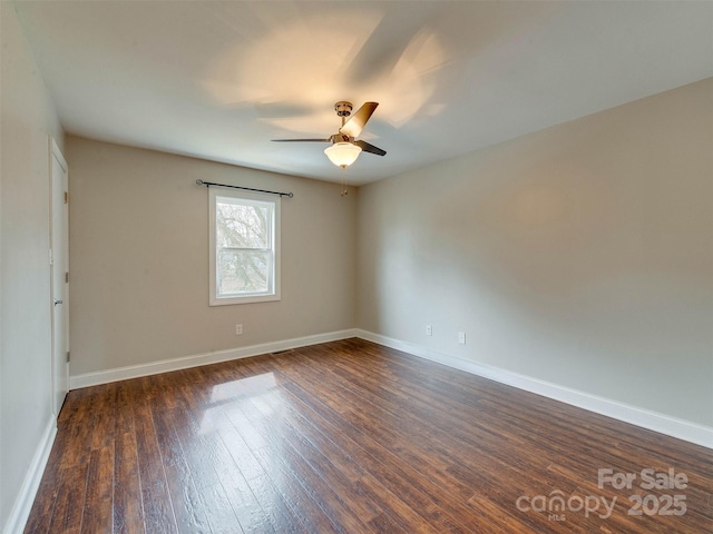 spare room featuring dark wood-style floors, a ceiling fan, and baseboards