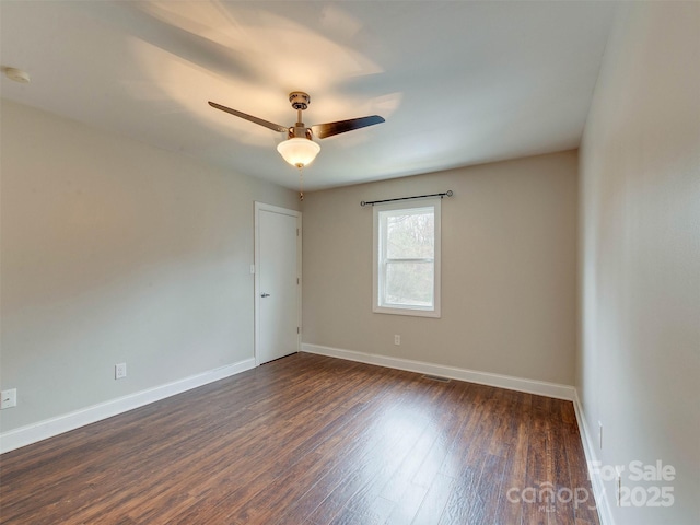 spare room featuring ceiling fan, dark wood-style flooring, and baseboards