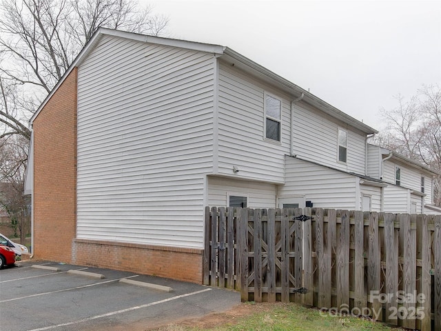 view of home's exterior featuring uncovered parking, fence, and brick siding