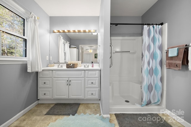 full bathroom with a shower stall, baseboards, and vanity