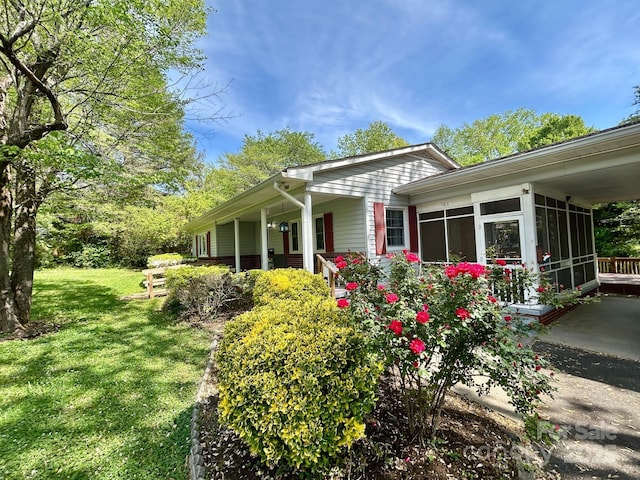 view of side of home with a sunroom and a lawn