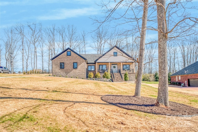 view of front of property with a porch, brick siding, and a front lawn