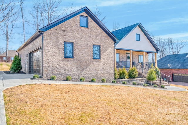 view of front of property featuring covered porch, a garage, brick siding, driveway, and a front lawn