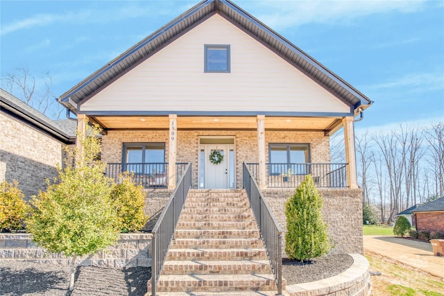 bungalow-style home featuring covered porch, stairs, and brick siding