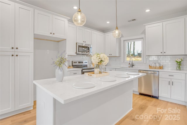 kitchen featuring appliances with stainless steel finishes, visible vents, a sink, and white cabinetry