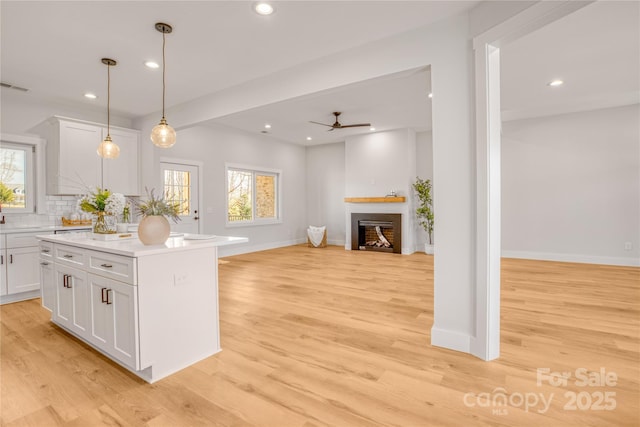 kitchen featuring recessed lighting, a fireplace, white cabinetry, light wood-style floors, and tasteful backsplash