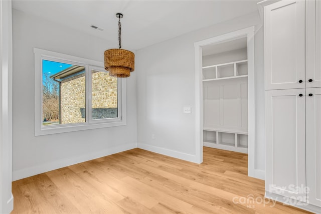 unfurnished dining area featuring visible vents, light wood-style flooring, and baseboards