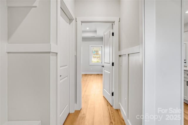 hallway with light wood-style flooring, baseboards, and recessed lighting