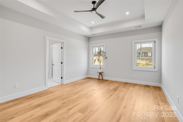 spare room with a raised ceiling, a healthy amount of sunlight, and baseboards