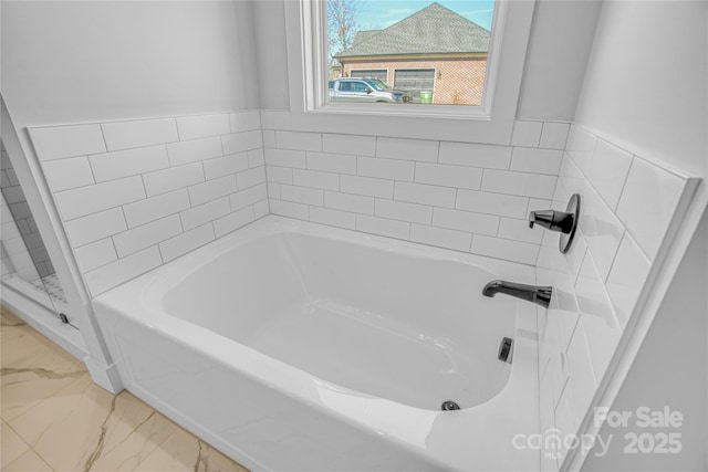 bathroom with marble finish floor and a garden tub