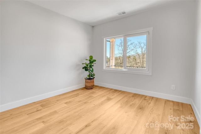 spare room featuring visible vents, baseboards, and wood finished floors