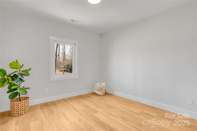 empty room with visible vents, baseboards, and wood finished floors