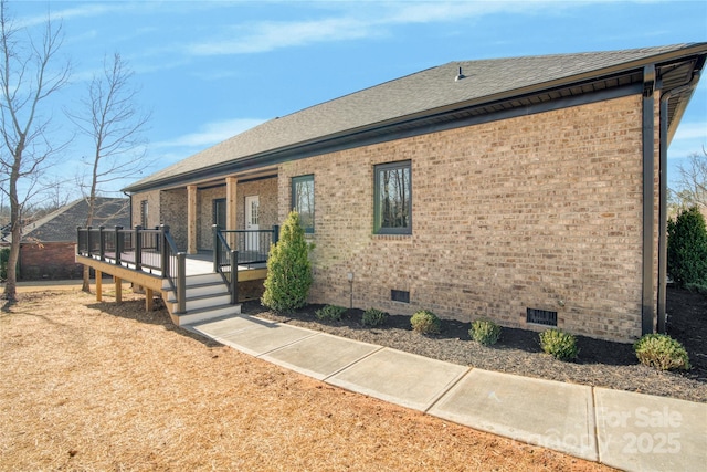 view of front of house featuring crawl space, a wooden deck, a shingled roof, and brick siding