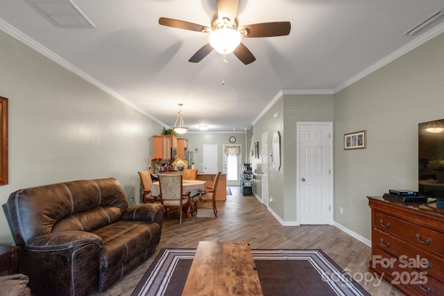 living room featuring light wood-type flooring, baseboards, visible vents, and ornamental molding