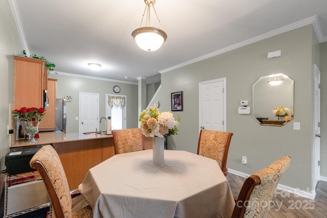 dining space with baseboards, wood finished floors, and crown molding