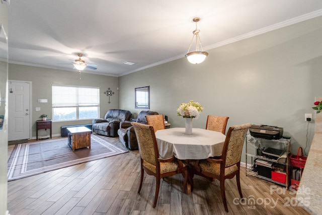 dining room with ceiling fan, ornamental molding, wood finished floors, and baseboards