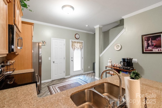 kitchen with stainless steel appliances, a sink, light countertops, and crown molding