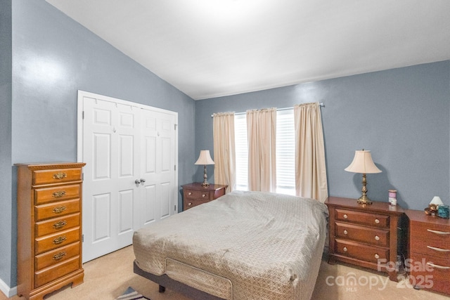 bedroom featuring a closet, light colored carpet, and vaulted ceiling