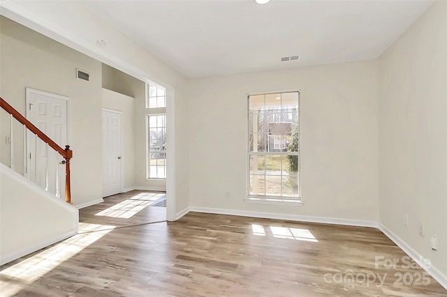 entrance foyer featuring light wood-style floors, baseboards, stairs, and visible vents