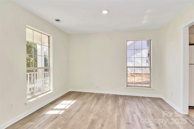 spare room with a healthy amount of sunlight, light wood-style flooring, and baseboards