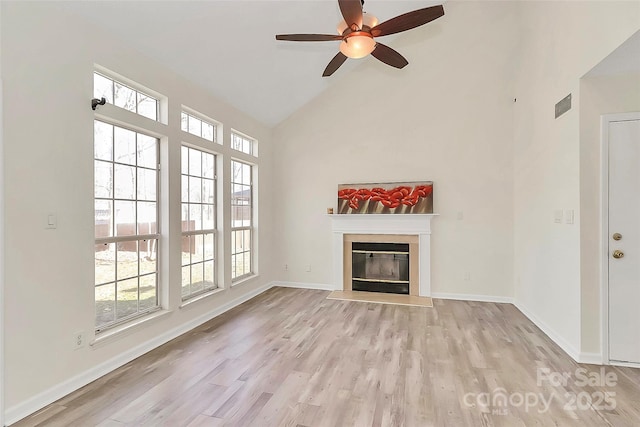 unfurnished living room with a fireplace with flush hearth, light wood-type flooring, and baseboards