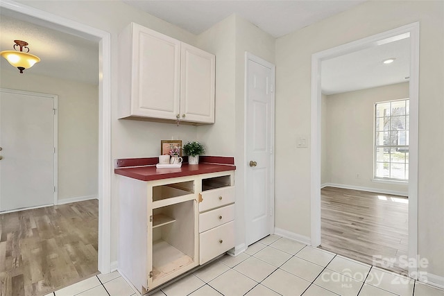 kitchen with baseboards, white cabinetry, and light tile patterned flooring