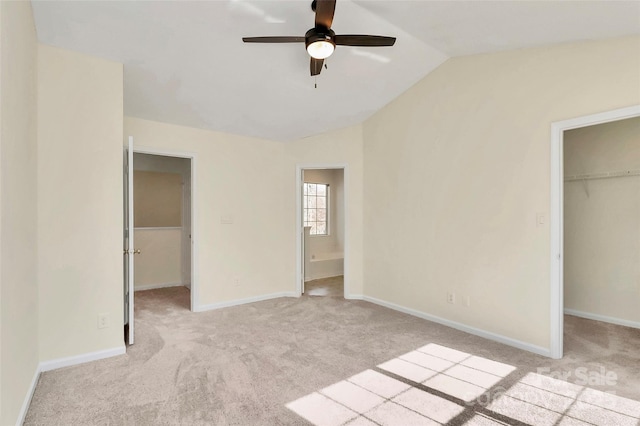 unfurnished bedroom featuring light carpet, vaulted ceiling, a walk in closet, and a closet