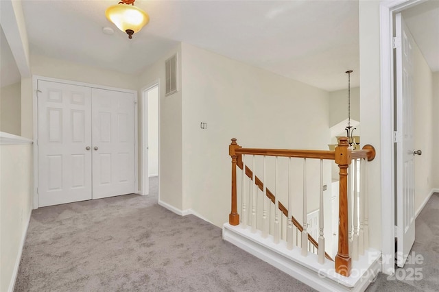 corridor featuring baseboards, visible vents, carpet flooring, and an upstairs landing