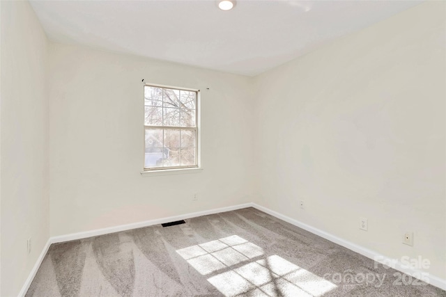 empty room with carpet, visible vents, and baseboards