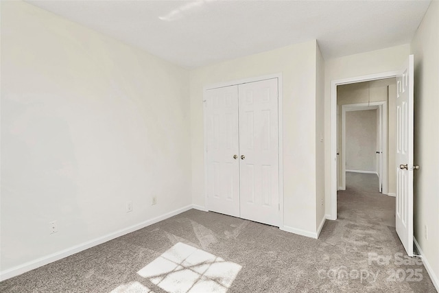 unfurnished bedroom featuring light carpet, baseboards, and a closet