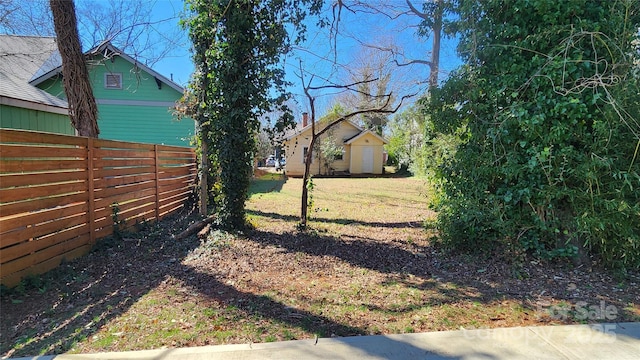 view of yard featuring an outbuilding, fence, and a shed