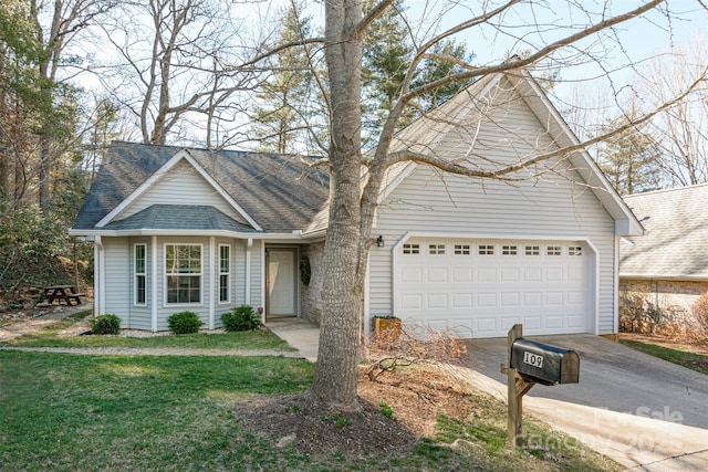 view of front facade with a garage, driveway, a front lawn, and roof with shingles