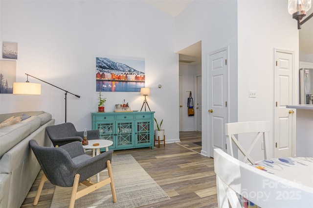 sitting room with a high ceiling, baseboards, and wood finished floors